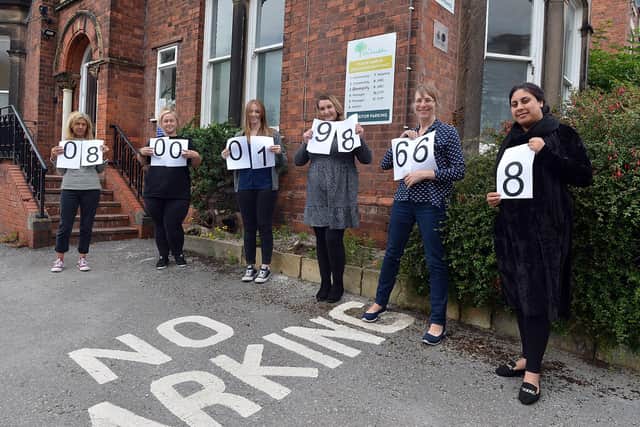Staff at Chesterfield's Elm Foundation hold the charity's helpline number. Pictures by Brian Eyre.