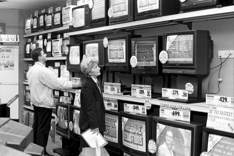 A man and and a female shop assistant with television sets and video cassette recorders in an unidentified Edinburgh electrical store, October 1988