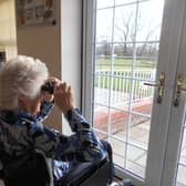 Residents of the care home are a picture of concentration and joy with binoculars in hand.