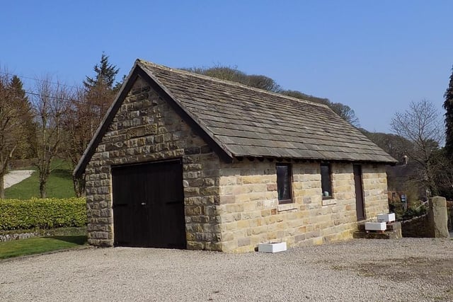 A large detached stone and tile garage/workshop outbuilding has double timber doors, power points and electric light.