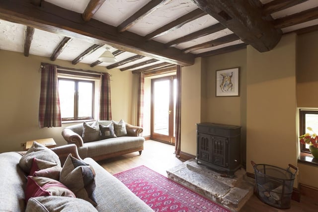 Exposed timber beams and timber effect flooring add rusticity to the lounge, with its cosy log burning stove and stone flagged hearth.