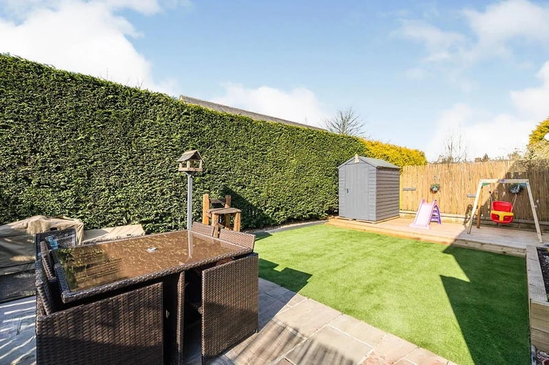 The rear garden is a mix of stone patio with raised flower beds, decking area and an artificial turf garden.