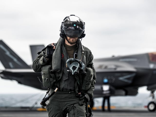 A British F-35B Lightning jet pilot walks across HMS Queen Elizabeth's flight deck with his fighter jet in the background. This image was part of the Peregrine Trophy winning selection from HMS Queen Elizabeth. By Leading Photographer Dan Shepherd