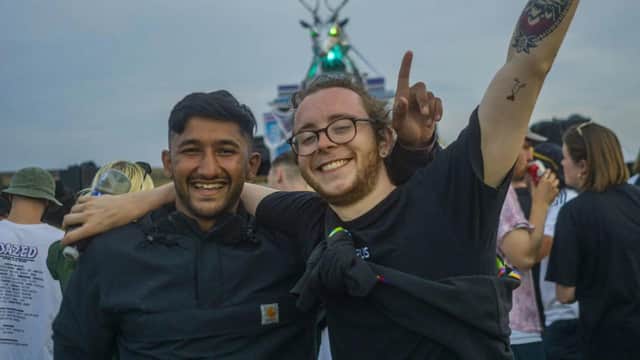 Festival-goers at the main stage where a stag's head sculpture crafted from recycled metals has laser beams radiating from its eyes.