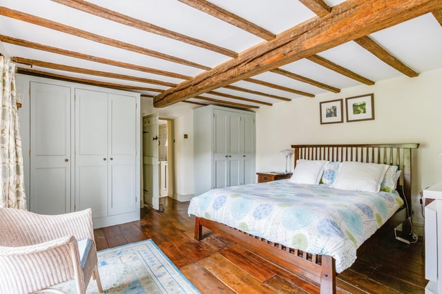 This spacious bedroom has two sets of fitted wardrobes, original wood strip flooring, stone fireplace and exposed beams.