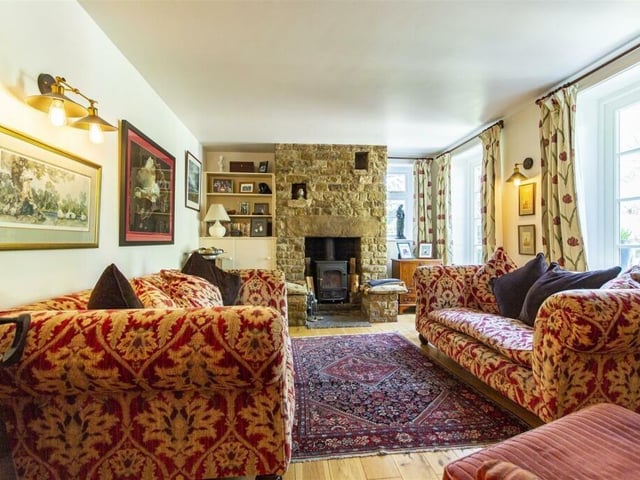 A multi-fuel stove sits in a stone fireplace in the lounge where there is solid wood flooring.