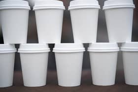 Disposable coffee cups are stacked on a table. Photo illustration by Christopher Furlong/Getty Images.