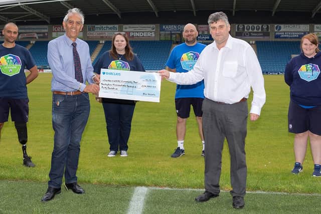 John Croot, chief executive of Chesterfield FC Community Trust, receives a cheque from Derbyshire PCC Hardyal Dhindsa, watched by Community Trust staff. Photo: Tina Jenner.