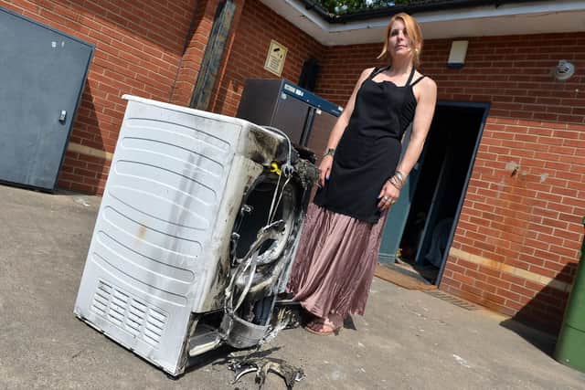 Rowan pictured with the burnt out tumble dryer which caused the blaze.