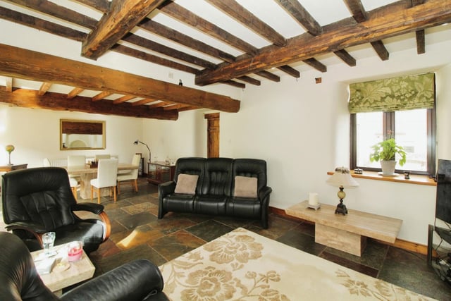 Let's begin our tour of the £900,000 Frithwood Farmhouse in Elmton by taking a look at the lounge/dining room. It is a lovely space with traditional ceiling beams, a slate floor with underfloor heating and a brick fireplace surround, with a recessed stove on a raised hearth.