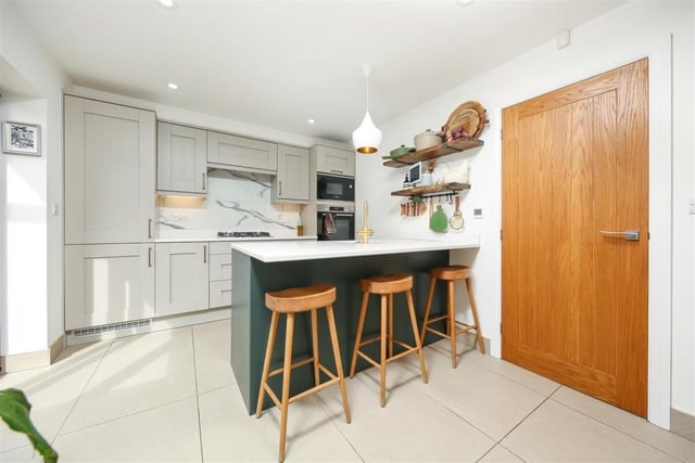 The kitchen is fitted with a breakfast bar and modern shaker-style storage units.