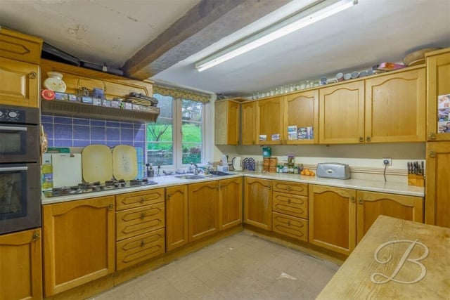 The kitchen has an extensive range of fitted storage units and an integrated double oven and gas hob with extractor fan above.