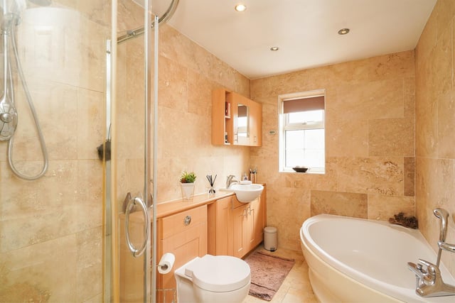The four-piece suite comprises corner bath, separate shower cubicle, hand basin inset within vanity unit, wc.