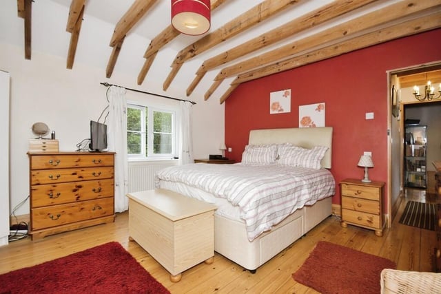 Exposed ceiling beams, a strip wooden floor and an ensuite shower room are features of the principal bedroom in the main residence.