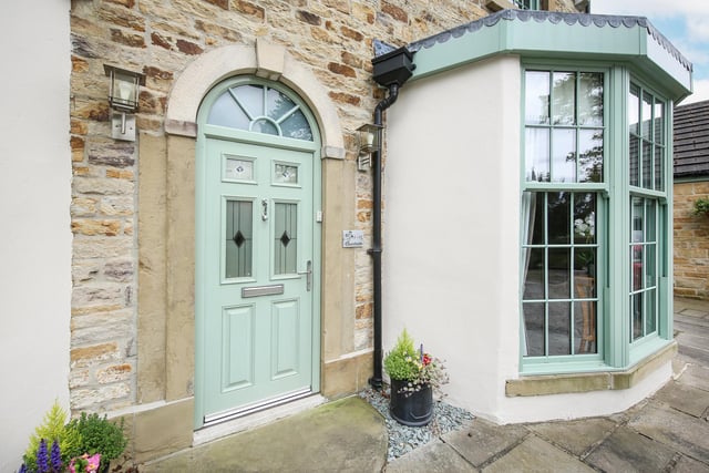 A stone arch frames the doorway between the property's distinctive bay windows.