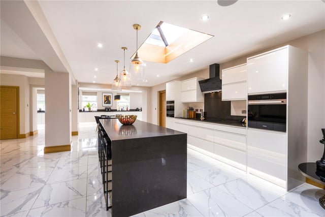 The spacious kitchen contains high gloss units with black quartz work surfaces. Appliances include four ovens, three wine fridges, two dishwashers, coffee machine, full-height fridge and full-height freezer. There is an under-counter fridge on the central island.