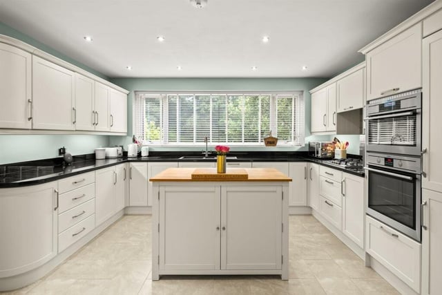 The well laid-out kitchen has wall and base storage cupboards galore, granite worktops and a central island.