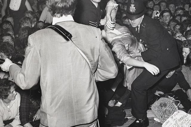 The Fab Four: John Lennon plays on as fainting Beatles fans are carried from the audience at Buxton's Pavilion Gardens in 1963