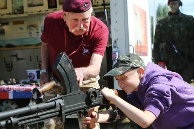 Former paratrooper Tom Turner shows Mason Vaughan a light machine gun