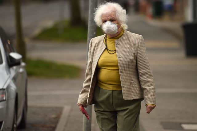 An elderly woman wearing a protective face mask leaves a newsagents (Photo by Oli SCARFF / AFP)