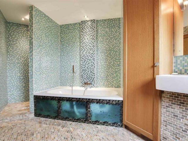 The bathroom has a low level flush WC, a vanity wash basin, a bath with chrome fittings and a handheld shower head, a shower enclosure, recessed spotlight, floor to ceiling tiles, underfloor heating, an extractor fan, built in floor to ceiling cupboards, a chrome heated towel rail and a double glazed window.