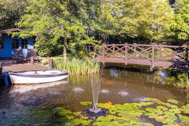The large carp pond, with mooring for a boat, is overlooked by a summer house and wooden bridge.