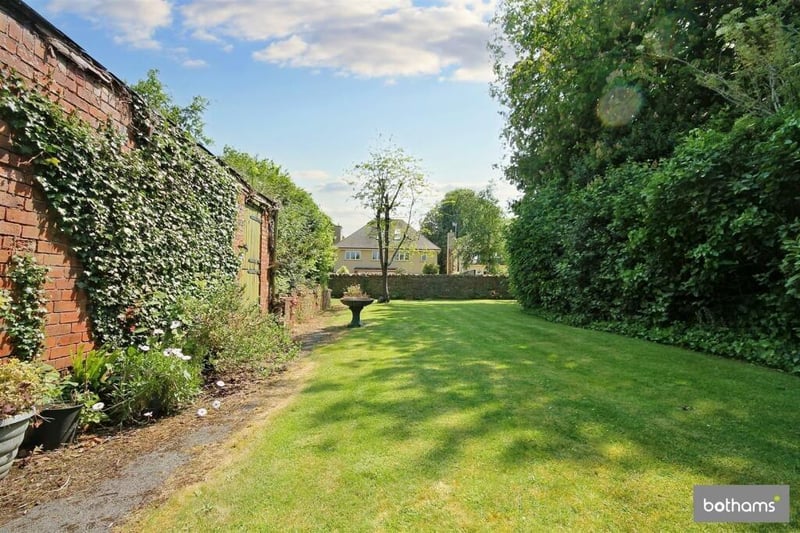 A large lawn at the back of the house with the detached coach house on the left of the photo.