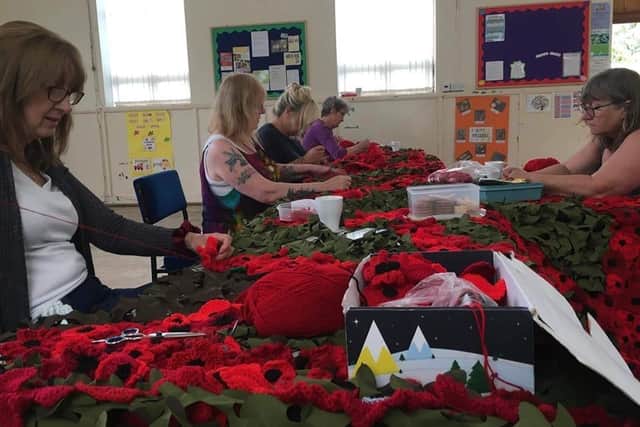 Julia Carr, Gill Parker, Sandra Riley, Ellen Tyler and Diane Richards sew the poppies to the net.