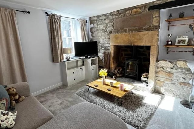 A substantial stone hearth housing a multi fuel stove is a focal point of the living room. The exposed stone wall accentuates the fireplace.