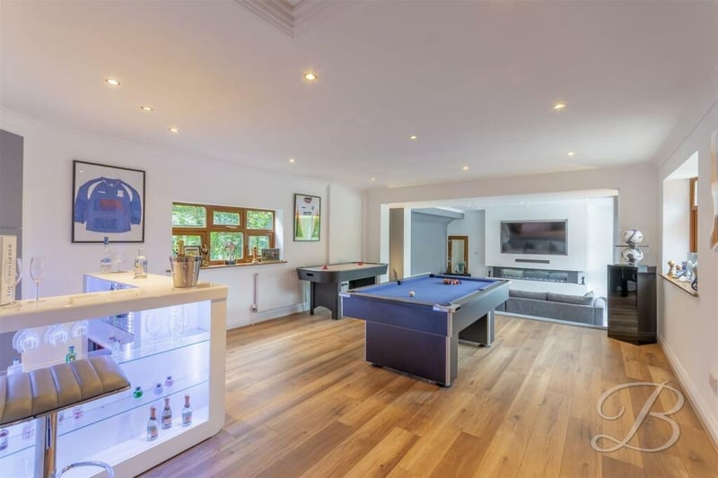 One of the highlights of the Huthwaite property is this spacious games room, with a contemporary, fitted bar that has shelving. As you can see, there is space for a pool table or snooker table. A laminated floor, downlights and windows to the front and back of the bungalow add to its appeal. The room also gives open access to the sitting room.