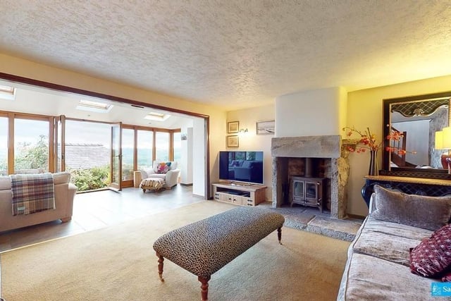Spacious and light, the sitting room  has panoramic views over the surrounding countryside. A multi-fuel stove sits on a raised hearth with dressed stone surround.