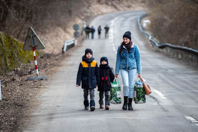 A woman with two children leave Ukraine and cross into Slovakia as fighting continues in Ukraine, causing millions to feel the country