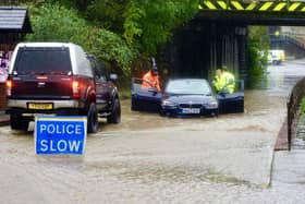 Emergency services help a driver stuck in deep flood water.