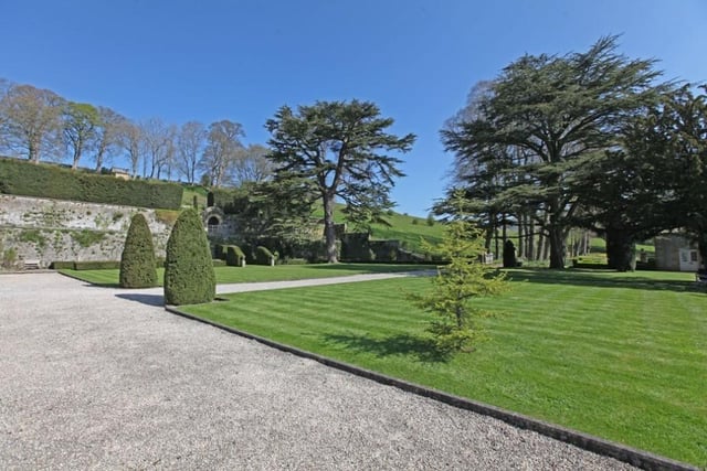 The flat lawns with gravelled pathways lead to the front of the house where there is a gently sloping lawn flanked by some fine yew topiary.