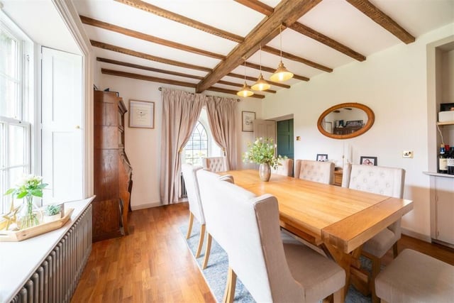 The dining room boasts a gothic arched window and exposed ceiling beams.