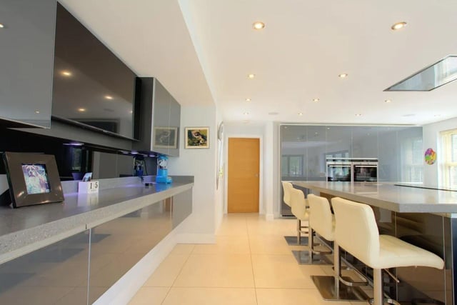 An open plan dining area and kicthen feature glass fronted charcoal coloured wall and base units, Corian work surfaces and several high quality integrated appliances.