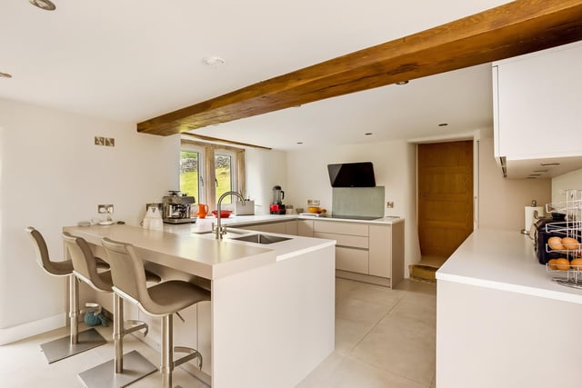 The taupe coloured fitted kitchen includes breakfast bar seating, five-ring inducton hob with extractor above, two self-cleaning electric ovens, dishwasher and refrigerator.