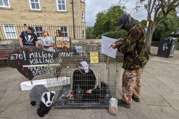 Pantomime of camo-wearing shooters brandishing guns, while a badger costumed protestor is trapped in a cage, brought to life the shocking reality of the cull.