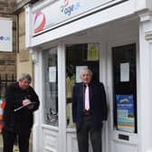 Graham Barnett with Councillor Mark Wakeman, of Derbyshire Dales District Council, signing the petition against the planned closure of the Age UK charity shop on Matlock Street, Bakewell.