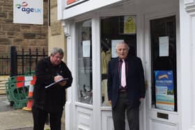 Graham Barnett with Councillor Mark Wakeman, of Derbyshire Dales District Council, signing the petition against the planned closure of the Age UK charity shop on Matlock Street, Bakewell.