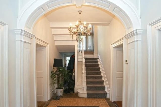 Elegant chandeliers illuminate the entrance hall which has an exposed stone floor.