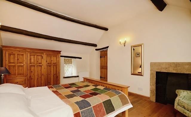 Ceiling beams and a fireplace with stone surround add character to this bedroom.