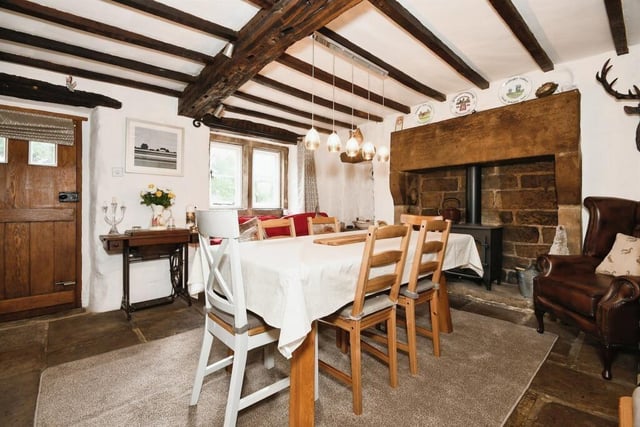 The dining room has a stone tiled floor, exposed beams on the ceiling and a log burner.