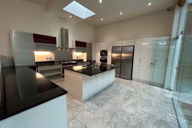 This well-designed kitchen is a showstopper, offering a central island with inset sink and fitted storage units wrapped around integrated appliances.