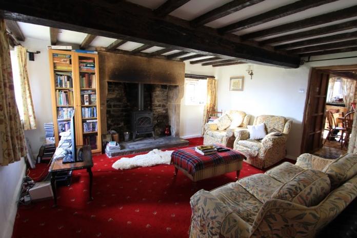 With a substantial ceiling beam and impressive cut stone fireplace with cast iron solid fuel stove. Mullioned windows to two walls and period cast iron radiator.