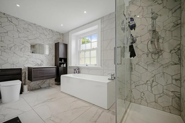 This contemporary bathroom offers a bath, separate shower cubicle, wall mounted wash basin and a wc.
