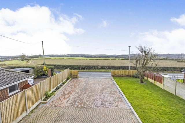 Stepping outside now, and here is the huge driveway that provides off-street parking space for more than ten vehicles and leads not only to the front of the house but also a secure garage. The image also shows the countryside views from the property.