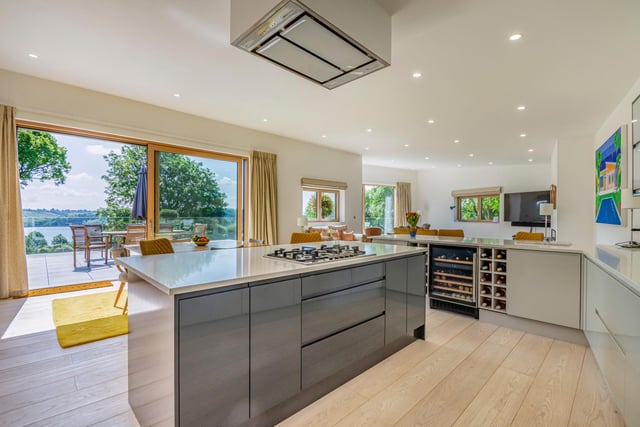 Just look at that spectacular view of the reservoir from the kitchen and dining area. The kitchen contains high-gloss storage units, a chef's island with gas hob and extractor above, two electric ovens, a microwave oven, a wine cooler, dishwasher and an undercounter fridge and freezer.