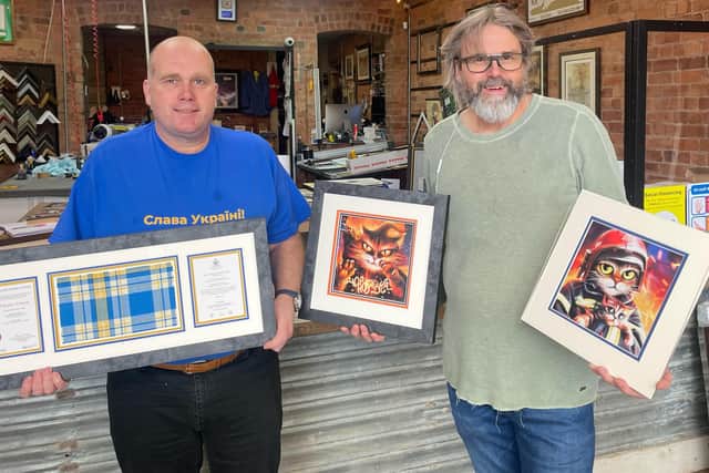 Darren Keyworth and Alwynn Morris with artwork and tartans they are selling off to help raise funds for relief efforts in Ukraine.