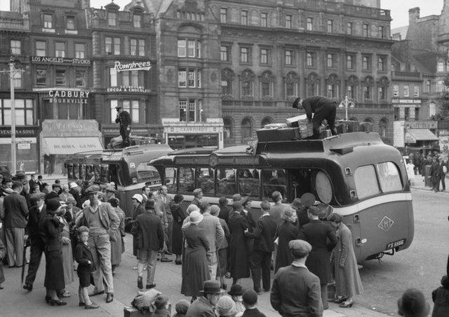 Near the Mound, throngs of passengers wait to board a pair of early SMT ‘luxury’ coaches, one of them London-bound. Holdalls are being secured to the roofs.